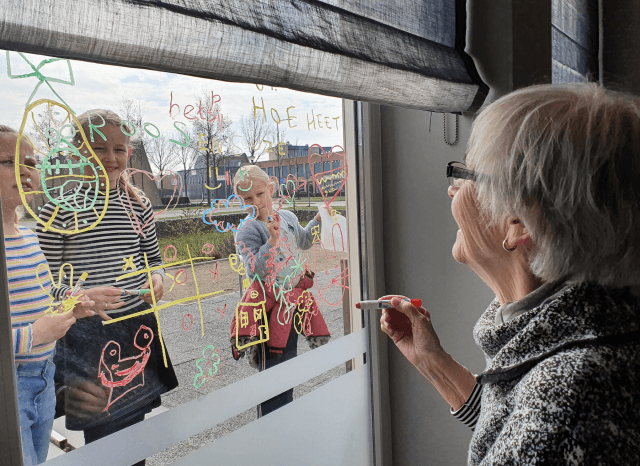 Kinderen de Linderte tekenen samen met oma op het raam